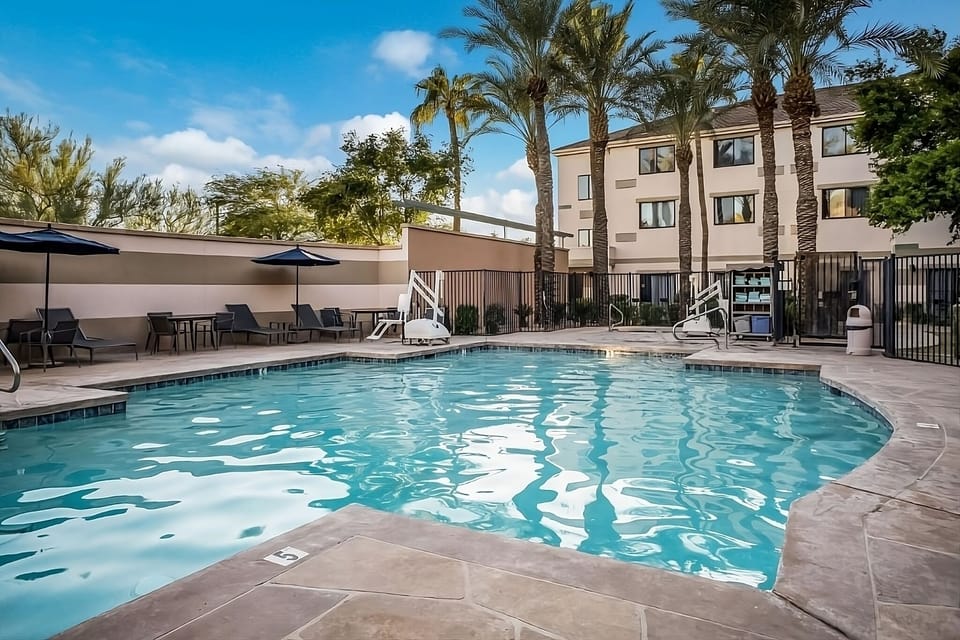 Dive into sunlit pool bliss surrounded by swaying palms.