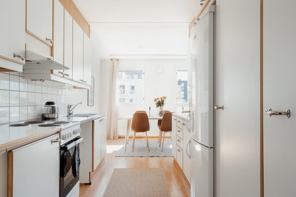 Modern kitchen with a full oven and extractor hood, opening through to the dining area.