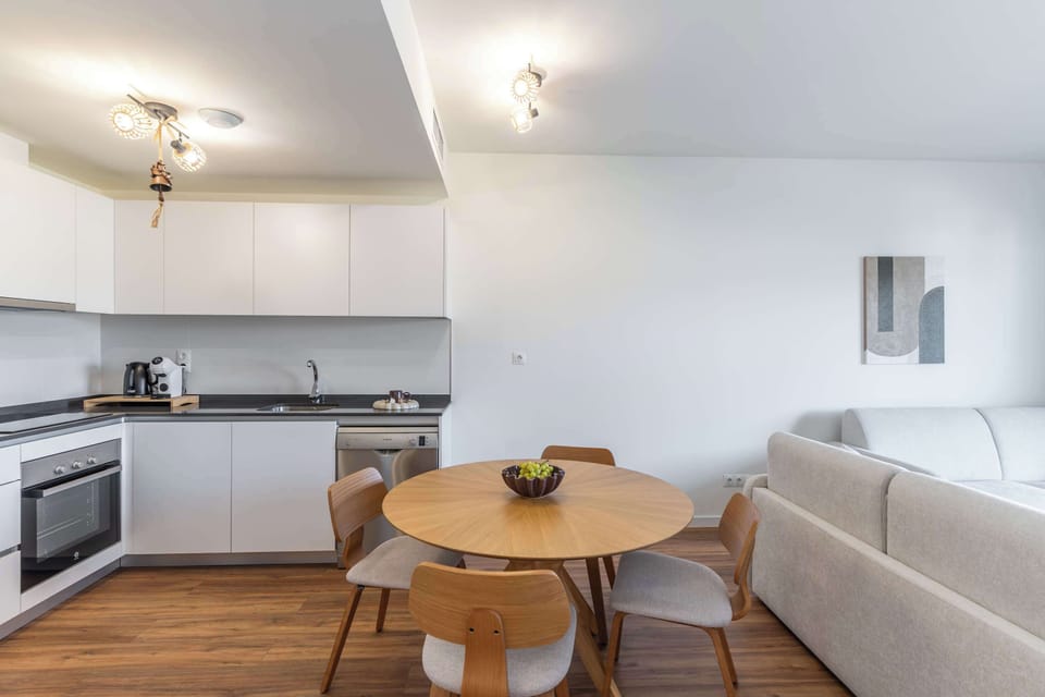 The kitchenette includes a fridge-freezer, induction hob, oven, microwave, dishwasher, kettle and coffee machine, along with essential cookware and tableware. A welcome set with coffee, tea and basic spices is also provided.