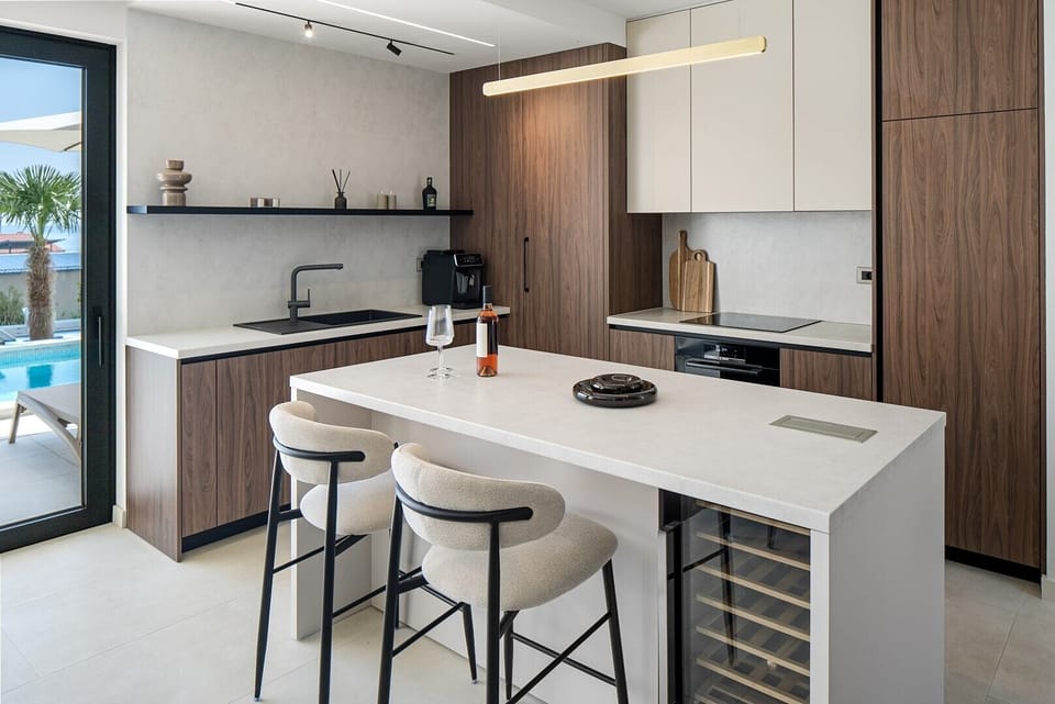 The fully stocked kitchen is equipped with modern appliances, including a microwave, coffee capsule machine, and all the essentials for a seamless stay