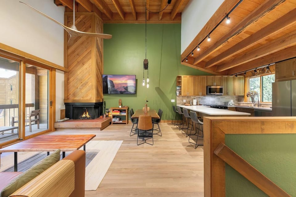 Open-concept great room with fireplace, vaulted wood ceilings, and island seating