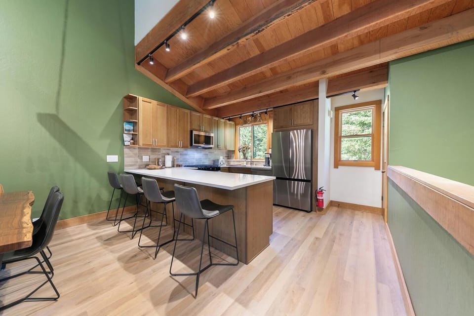 Bright vaulted kitchen with wood beams, island seating, and modern finishes