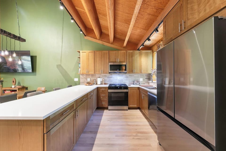 Stylish open kitchen with vaulted wood ceilings and a spacious island