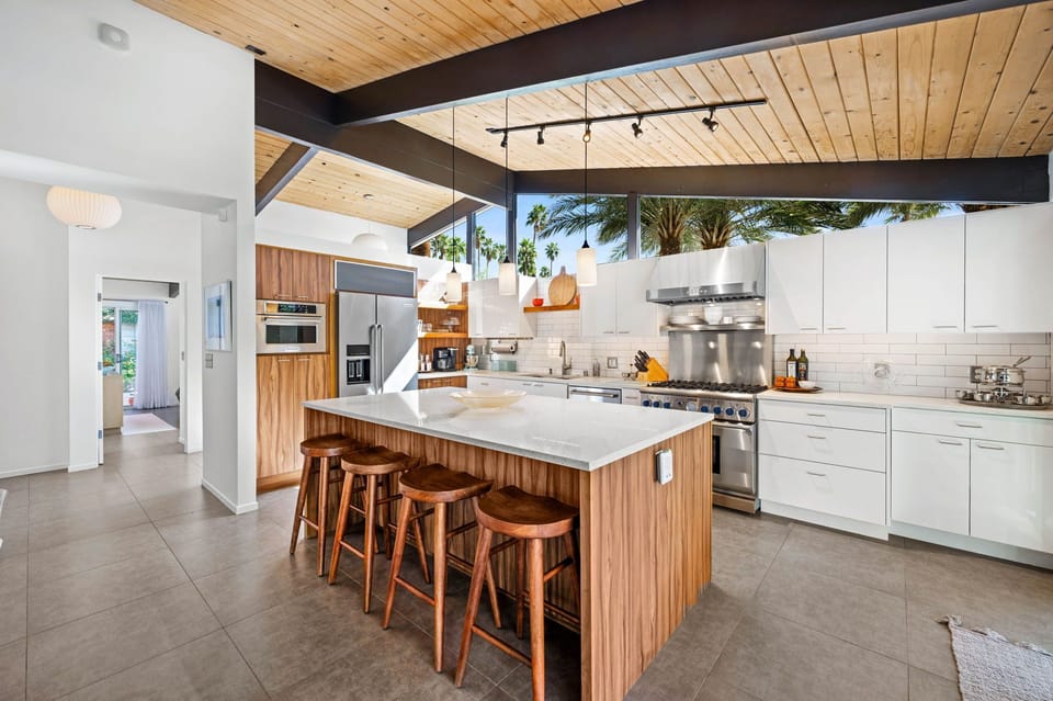 Cook in this stunning modern kitchen featuring a spacious island, premium appliances, and warm wood accents under soaring exposed beam ceilings.