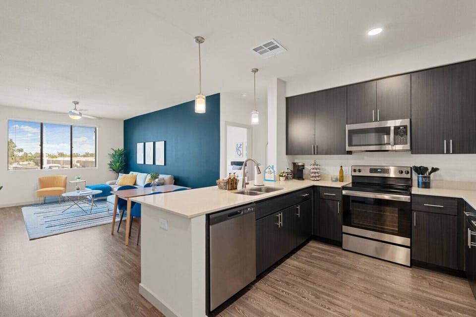 This stylish space features a fully equipped kitchen with stainless steel appliances, a comfortable living area with a large window, and a dining area perfect for meals.