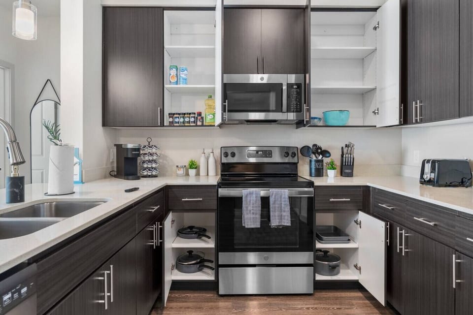 Prepare delicious meals with ease in this fully equipped kitchen, featuring stainless steel appliances, a convenient coffee station, and all the necessary cooking supplies.