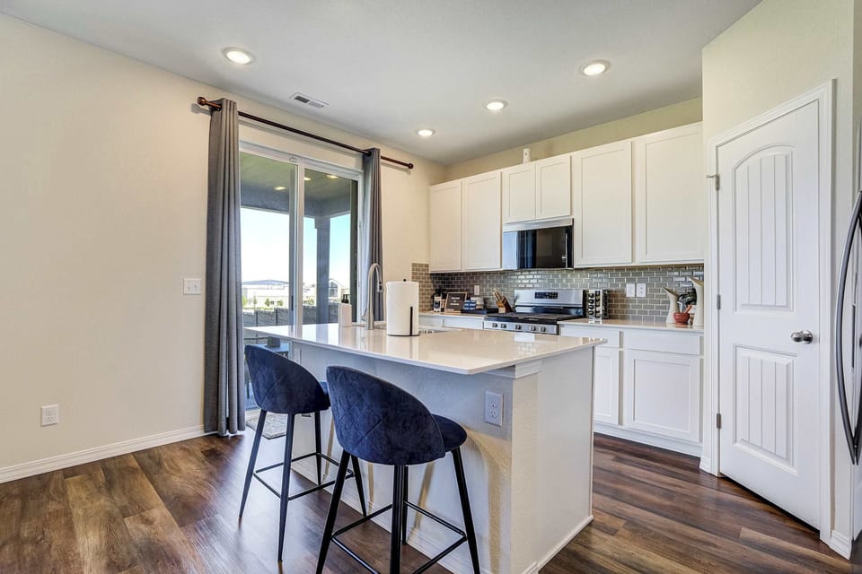 This fully stocked kitchen features white cabinetry, quartz counters, and a gray subway tile backsplash throughout. A stainless refrigerator and ample counter space make cooking for the group easy during your stay.