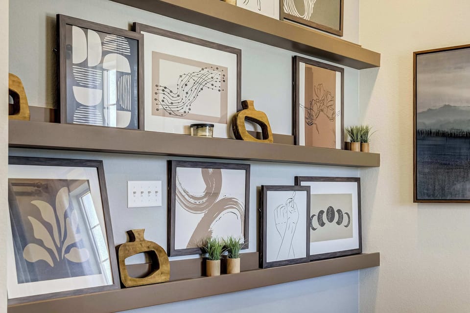A closer look at the layered shelving reveals a mix of framed prints, sculptural accents, and decorative touches. This styled display brings a gallery like feel to the office, making the space as visually interesting as it is functional.