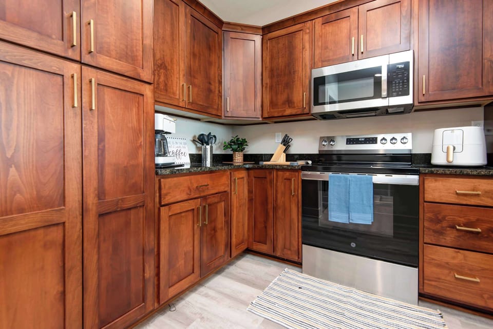 Modern kitchen featuring a stainless smooth-top stove and microwave, perfect for easy meal preparation, quick snacks, and convenient vacation dining.
