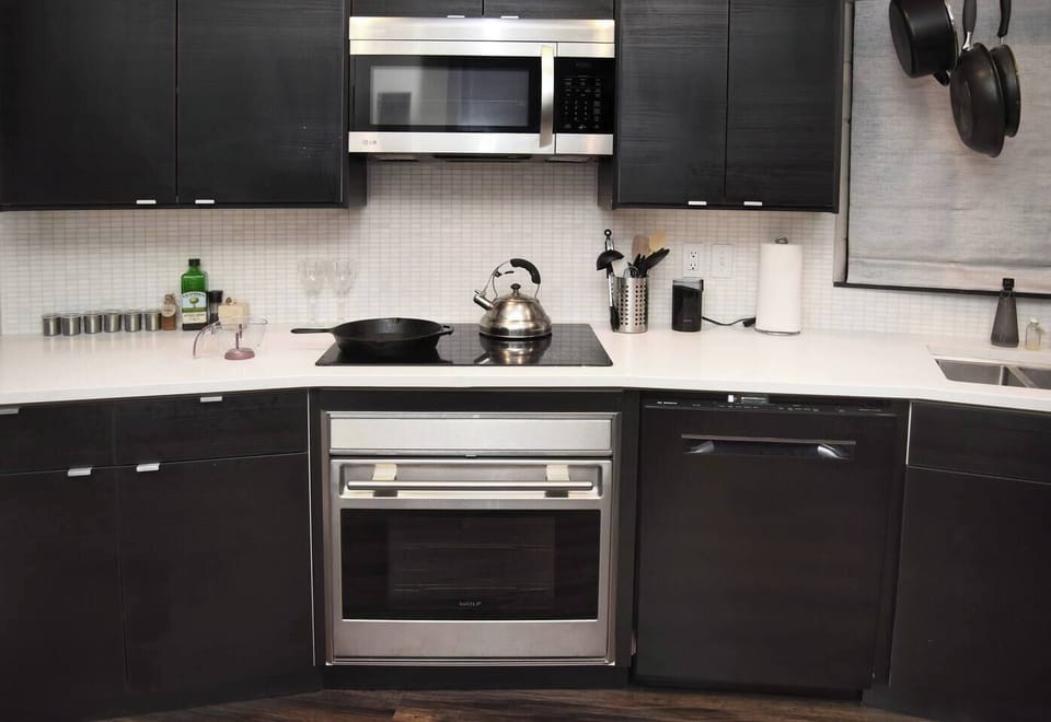 The kitchen is fully stocked with appliances (oven, glass electric cooktop, microwave) and supplies (pots, pans, utensils, and coffee bean grinder) to prepare a full meal!