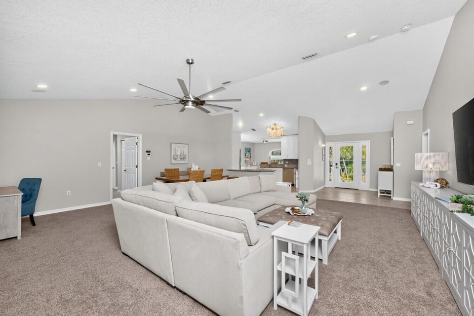 Expansive open-concept living area with vaulted ceilings, oversized sectional, Smart TV, dining space, and seamless access to the fully equipped kitchen—designed for comfortable group gatherings near Manasota Key Beach.