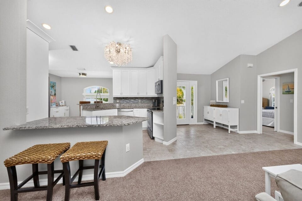 Bright, fully equipped kitchen with granite countertops, breakfast bar, stainless steel appliances, and open-concept design connecting seamlessly to the living area and entry foyer—perfect for entertaining near Manasota Key Beach.