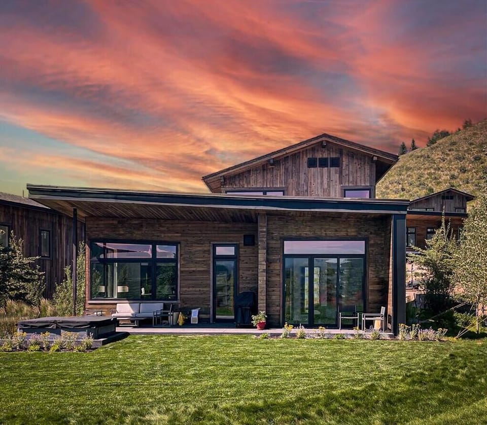 Cabin exterior at sunset, with mixed wood siding and a hillside backdrop