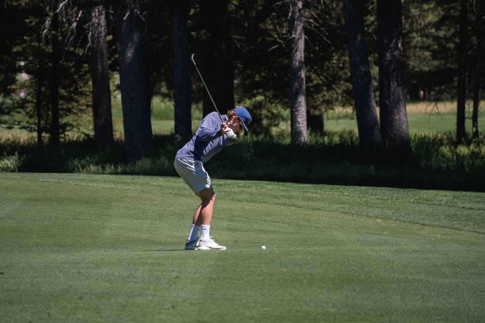 Mid-swing on the Tom Weiskopf-designed 18-hole championship course, with mountain ridgelines in every sightline