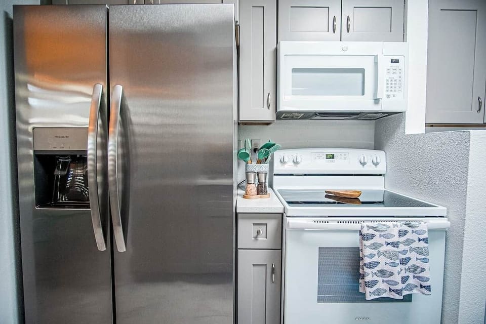 Fully equipped kitchen featuring a stainless steel refrigerator with filtered water dispenser and ice maker, plus microwave, oven, and freezer.