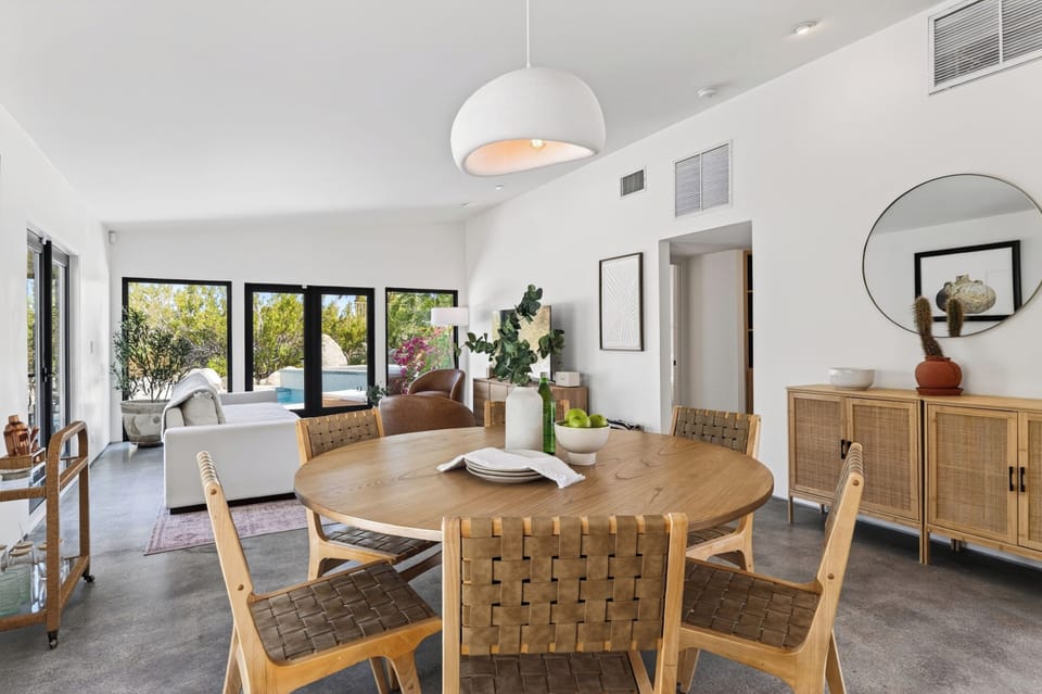 Sophisticated dining area centered around a warm wood table under an elegant contemporary pendant light.