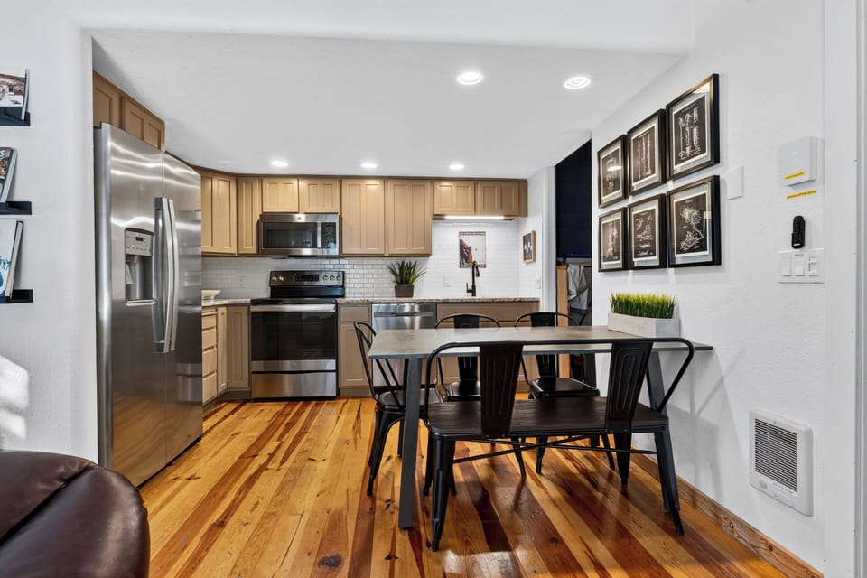 Dining area with a modern black metal table and chairs, opening up to the kitchen.