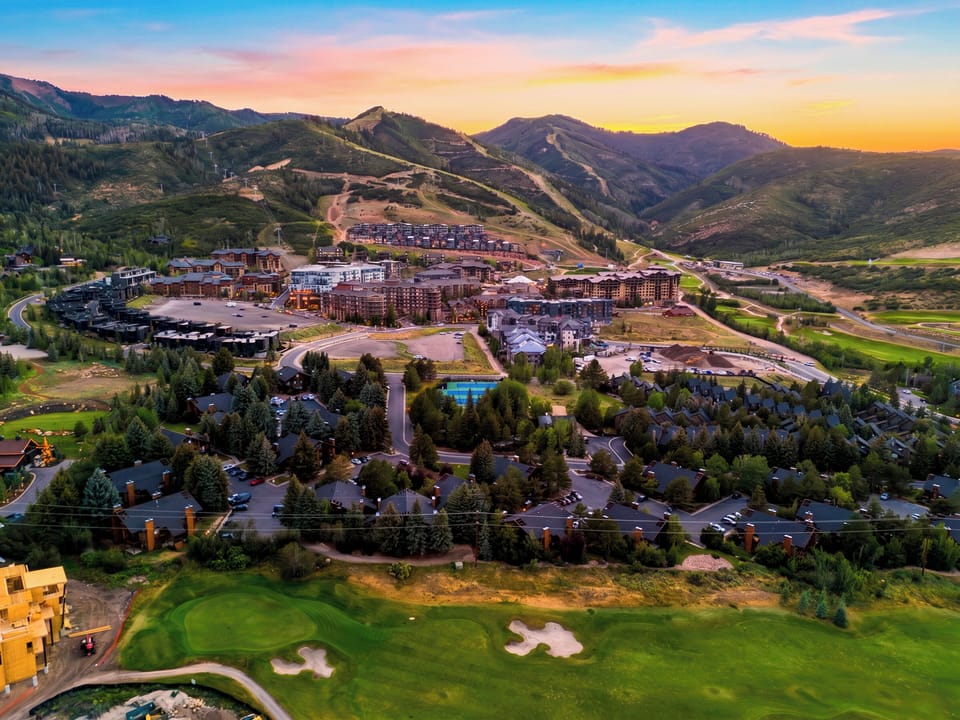 Aerial drone shot of the surrounding mountain resort community at sunset.