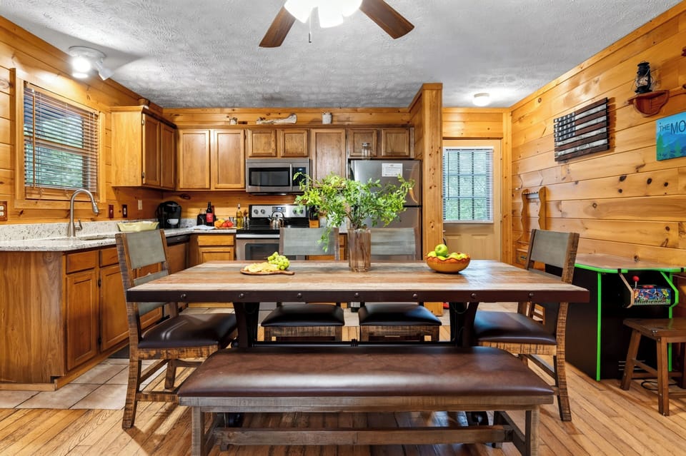 Dedicated dining space with a large wooden table, bench, high-back chairs, and an adjacent full kitchen.