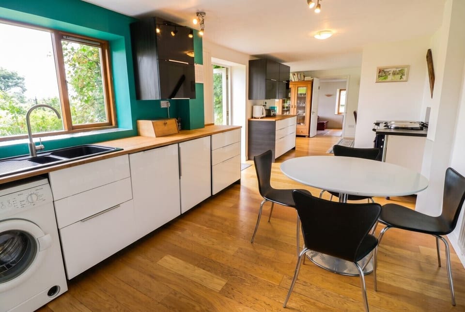Bright kitchen with breakfast table and leafy views over the sink