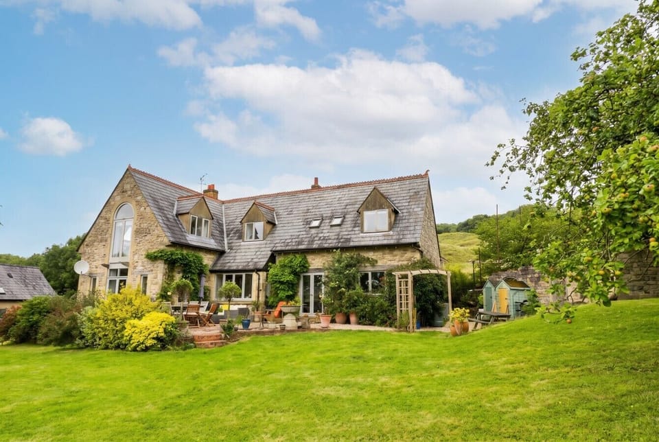 Stone country home nestled below the hills with a sweeping garden