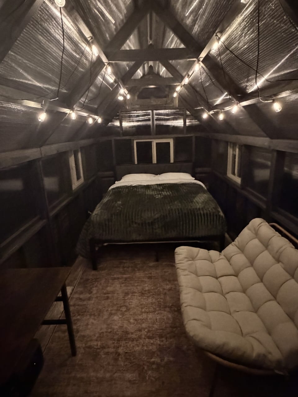 Cozy A-frame loft with warm string lights, futon, and rustic charm