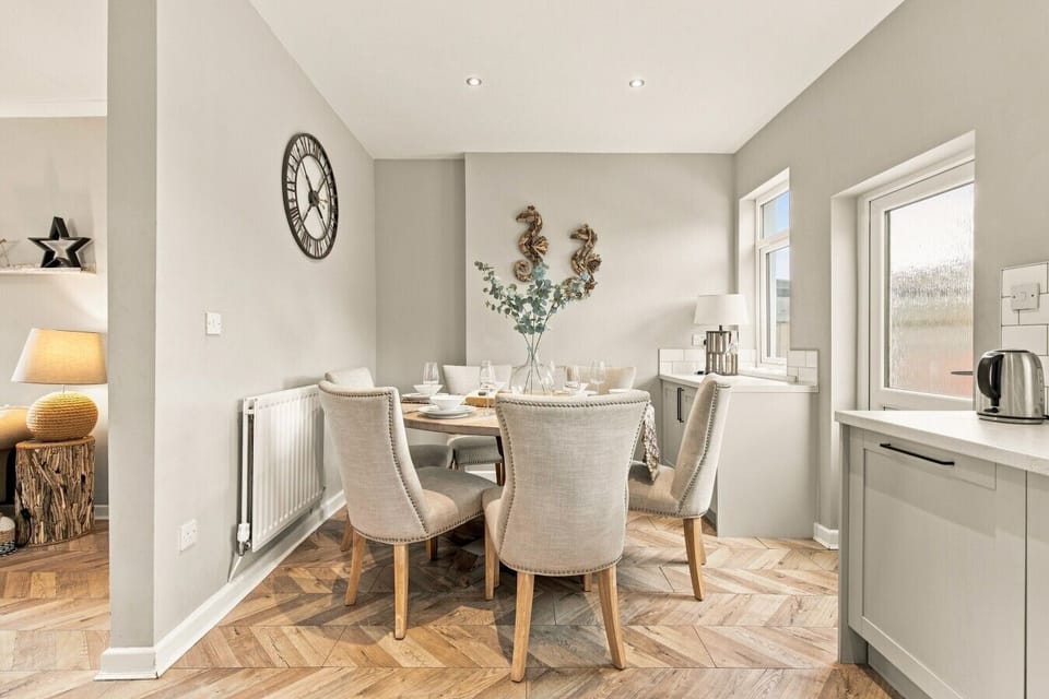 Dining area with upholstered chairs and windows overlooking the garden.