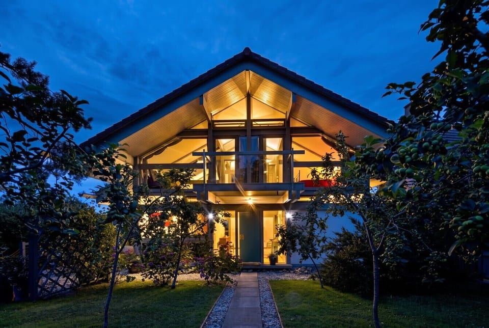 Striking timber-framed home glowing warmly at dusk against the evening sky.