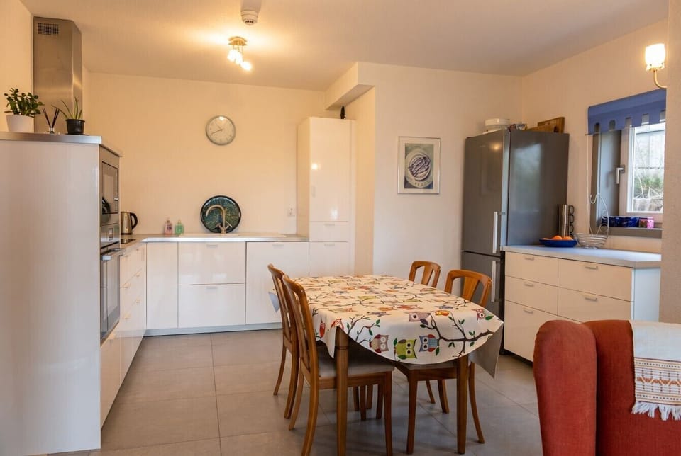 Sleek white kitchen and dining space, ideal for cooking together.