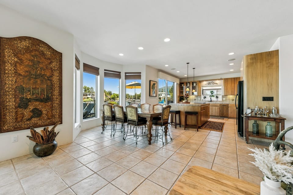 Gather around this sun-drenched dining table with views that bring the outdoors in. Your fully equipped kitchen awaits, complete with modern appliances and warm wood cabinetry, perfect for preparing meals together.