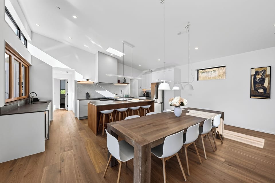 Open-concept main living space showcasing a wooden dining table with seating directly adjacent to the large kitchen island.
