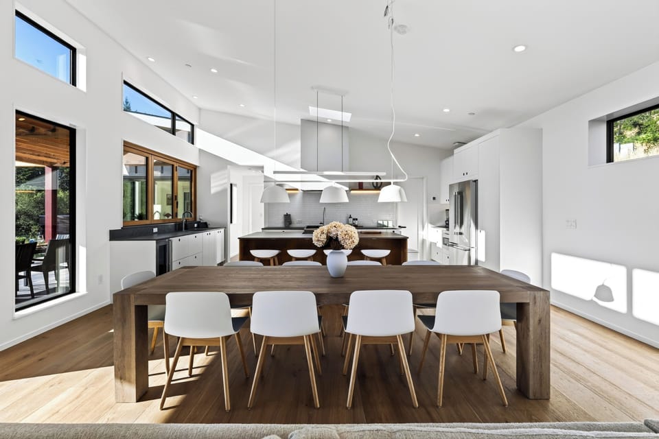 Dedicated dining space featuring a thick wooden dining table surrounded by modern white chairs under sleek pendant lighting.