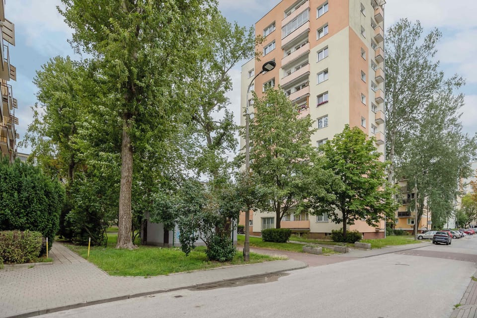 Exterior view of the apartment building surrounded by mature trees and greenery.