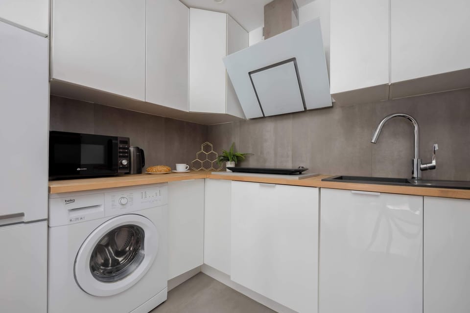 Modern open-plan kitchenette with built-in appliances, wooden countertops, and practical layout.