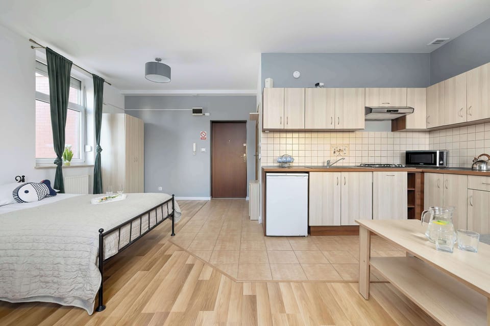 Spacious studio apartment with a queen bed, modern kitchenette, dining area, and comfortable living space.