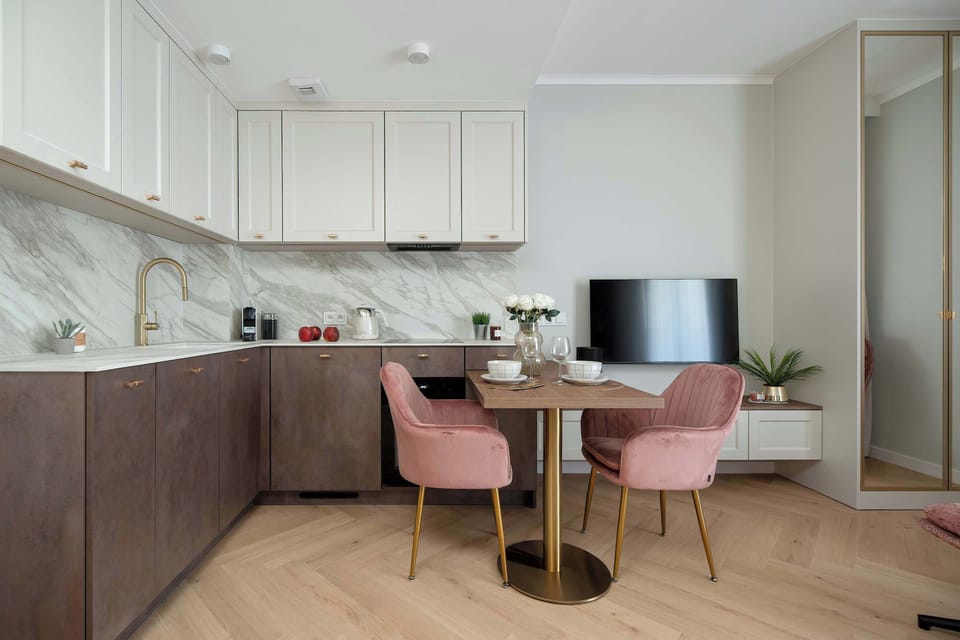 A modern kitchenette with a dining table and pink chairs. The bright interior offers a stylish and functional space.