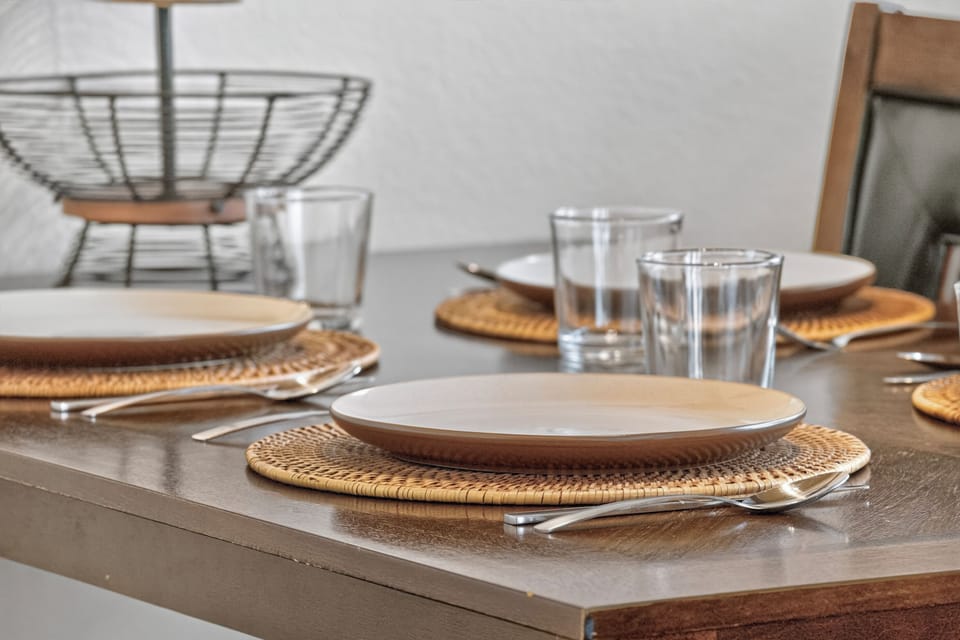Your dining table is beautifully set with warm woven placemats and elegant tableware, ready for shared meals and memorable conversations in your home away from home.