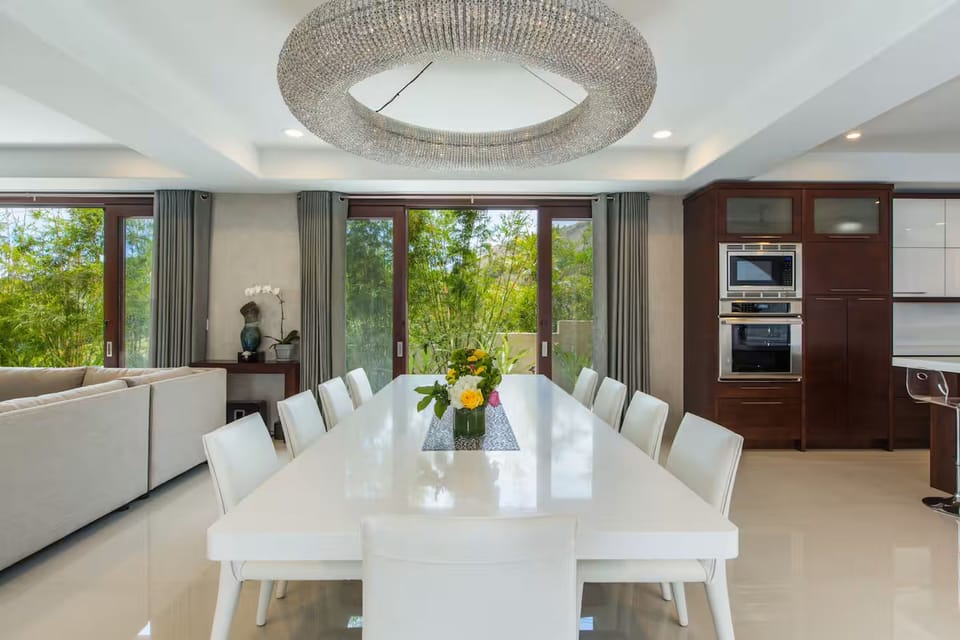 One long table and a sculptural chandelier gather the whole group for dinner.