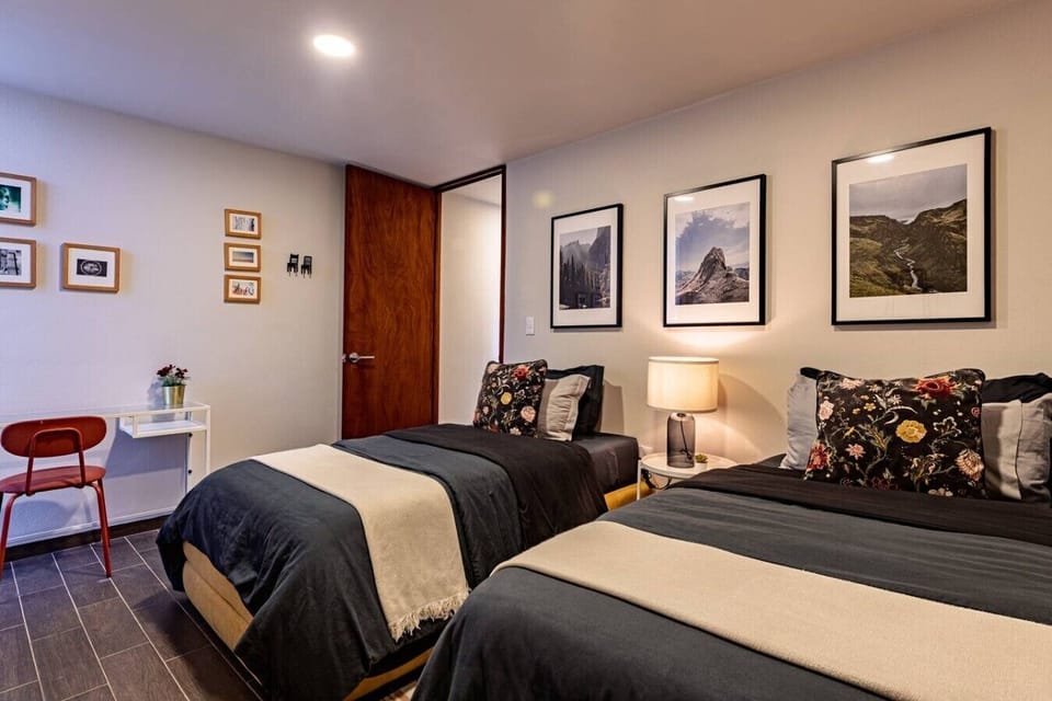 Comfortable bedroom with two single beds and a workspace area.