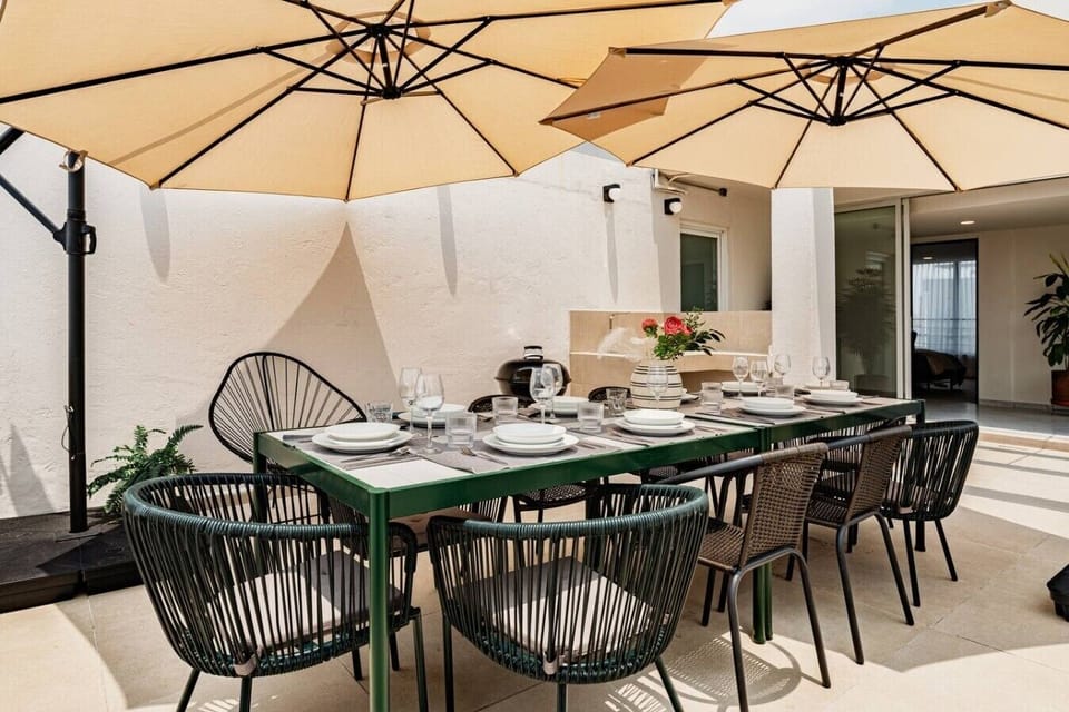 Private outdoor dining area with seating area, beneath large umbrellas.