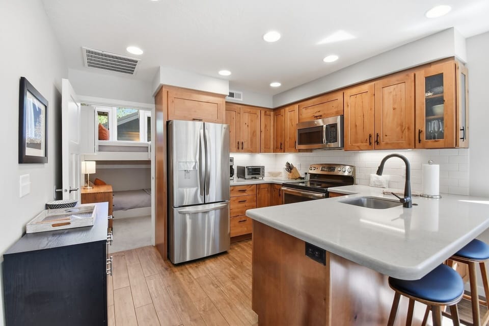 Your fully equipped kitchen features warm wood cabinetry, gleaming countertops, and modern stainless appliances—perfect for whipping up meals while enjoying the bright, airy space.