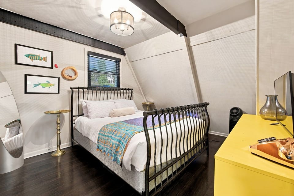 Downstairs bedroom - complete with a Queen-size bed, closet, dresser, Smart TV, and nearby shared bathroom.
