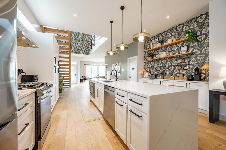 Bright chef's kitchen - quartz waterfall island, gas range, open shelving, and an exquisite curated coffee bar stocked with creative options.
