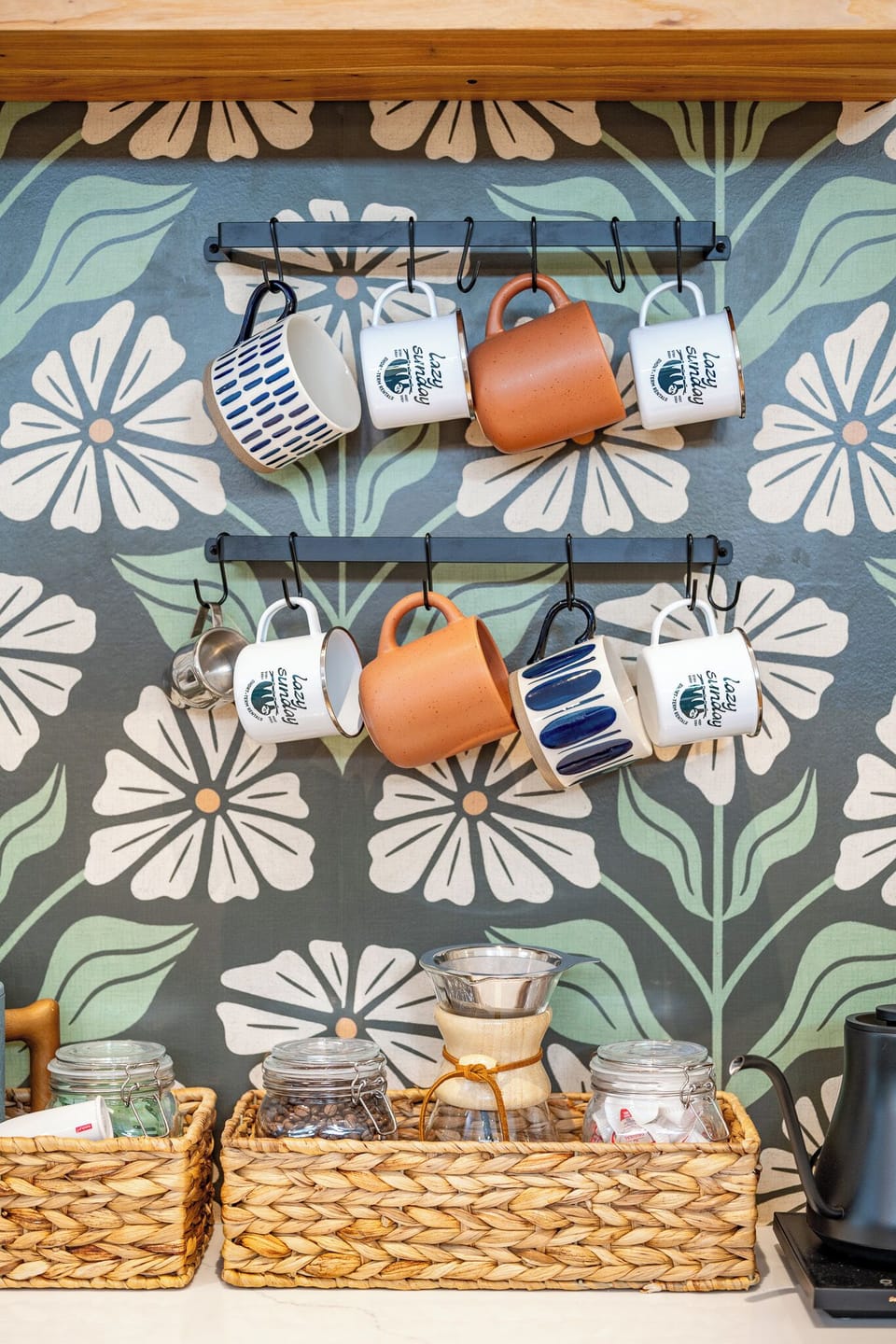 Stylish coffee nook with bold wallpaper, hanging mugs, and pour-over setup