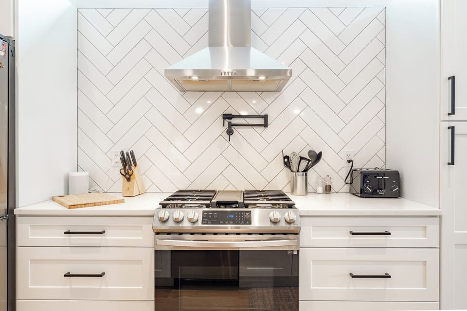 Modern chef’s kitchen with gas range and stylish herringbone backsplash