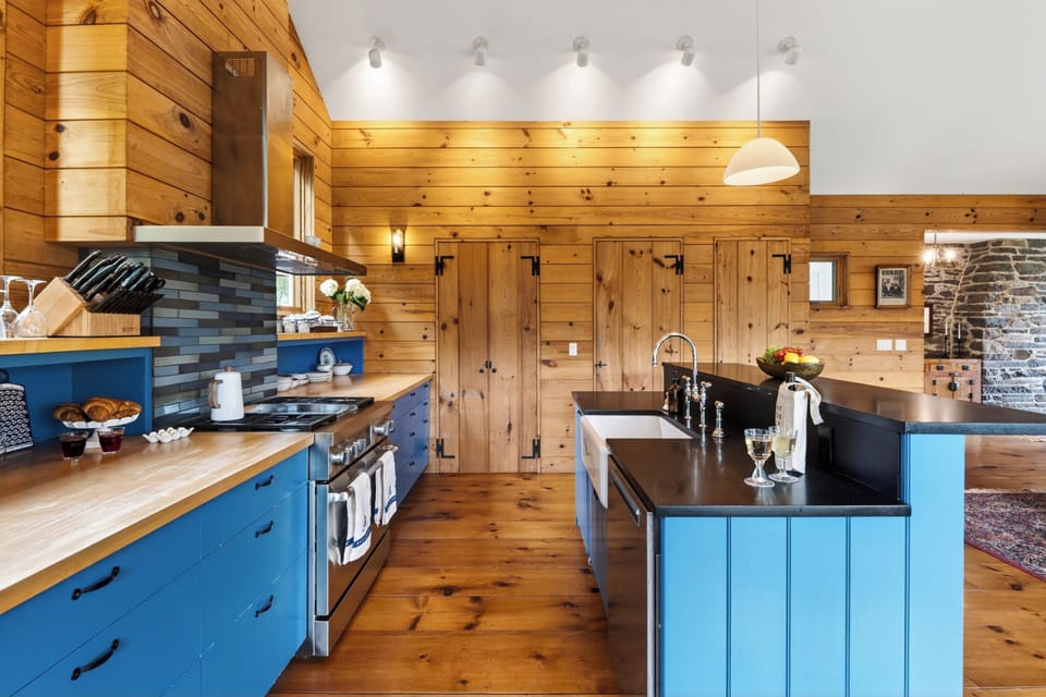 Warm wood kitchen with bold blue cabinetry, vaulted ceilings, and generous island prep space.