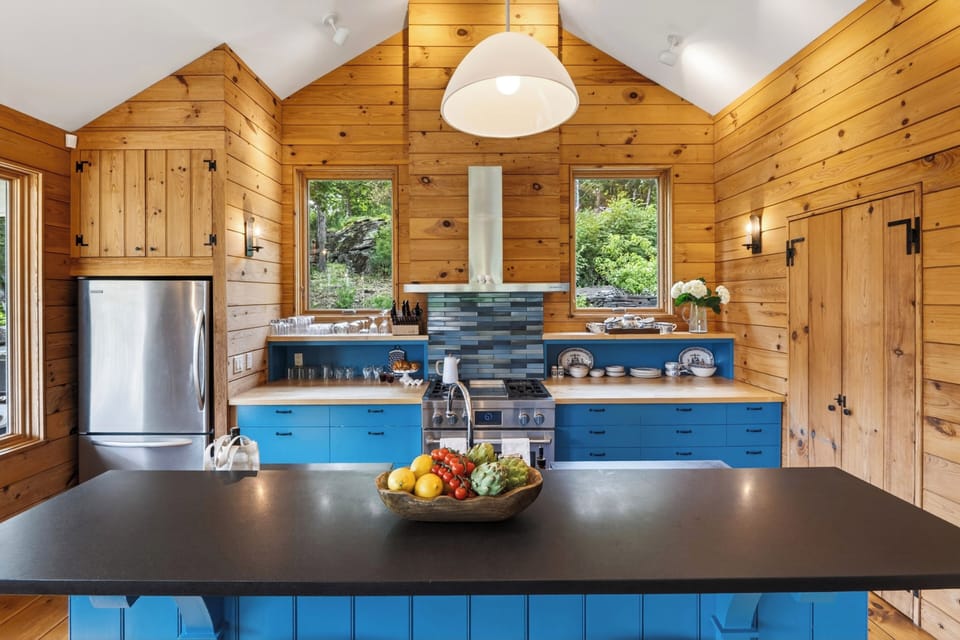 Warm wood kitchen with bold blue cabinetry, vaulted ceilings, and generous island prep space.