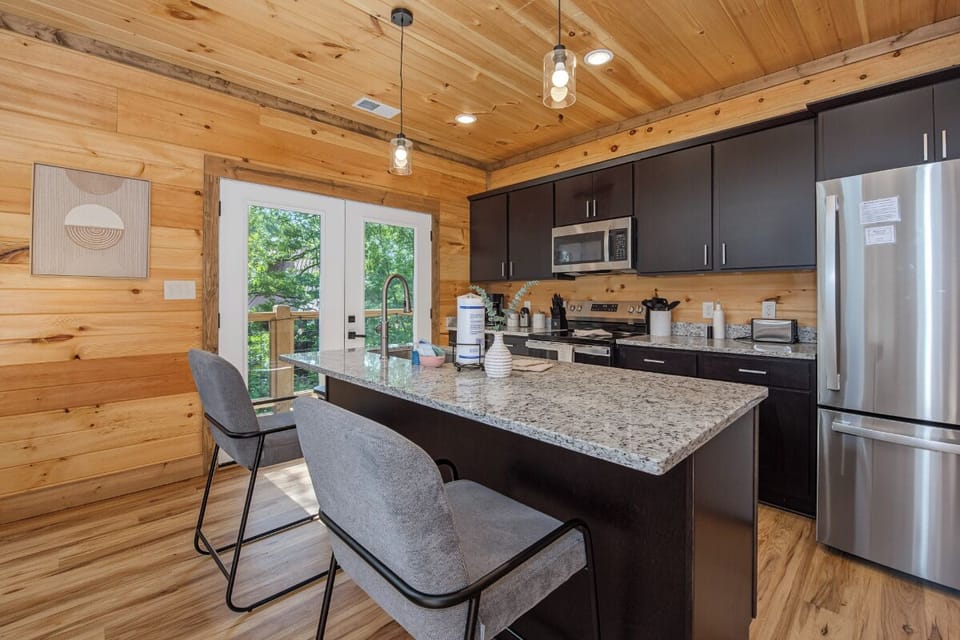 Gather around your spacious kitchen island with modern appliances and sleek granite counters. Natural wood walls and pendant lighting create a warm, inviting atmosphere for meal prep and morning coffee.
