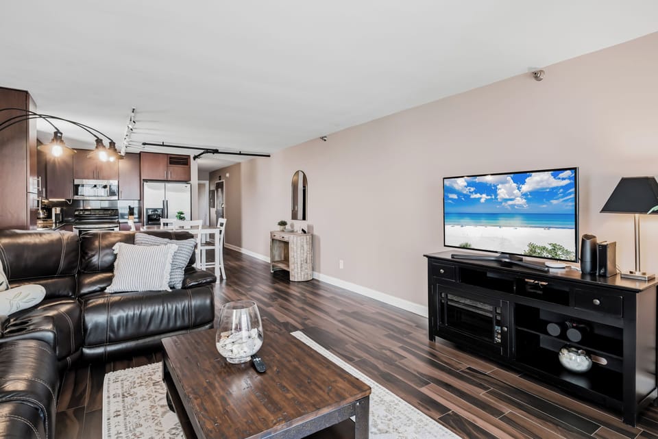Unwind in your spacious living area with rich wood floors, plush leather seating, and modern entertainment—perfect for cozy evenings after exploring the coast.