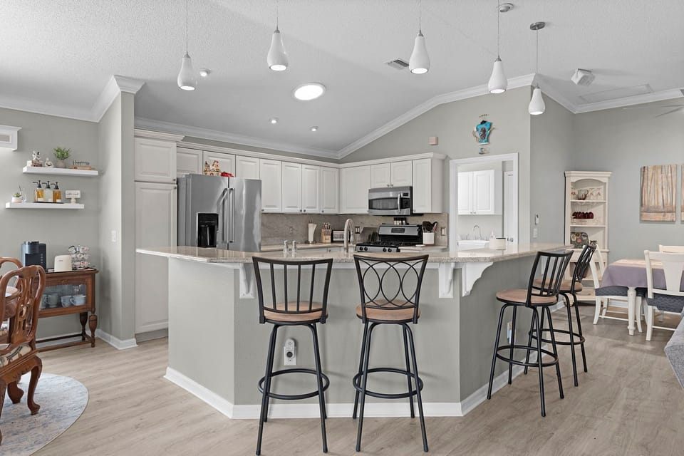 Pull up a seat at the sleek breakfast bar, where soft pendant lighting and thoughtfully stocked countertops set the stage for your morning coffee or casual meals together.